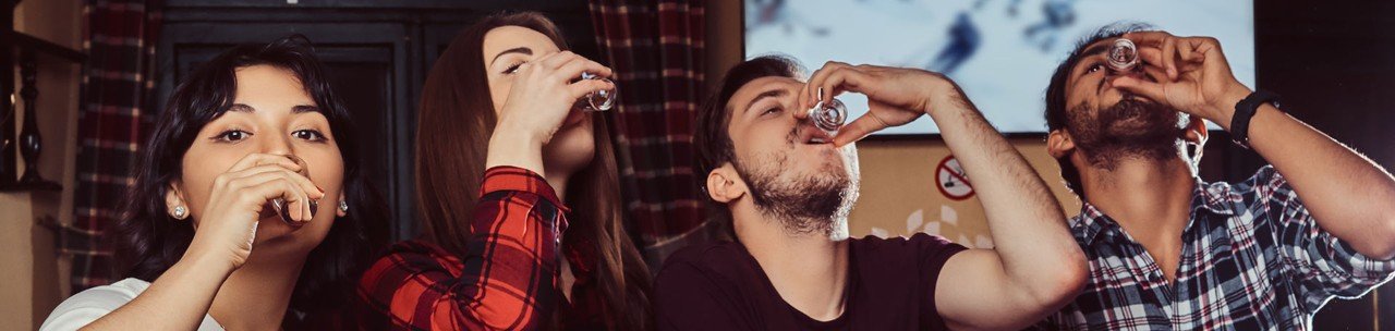 jovens amigos multirraciais bebem vodka descansando no pub