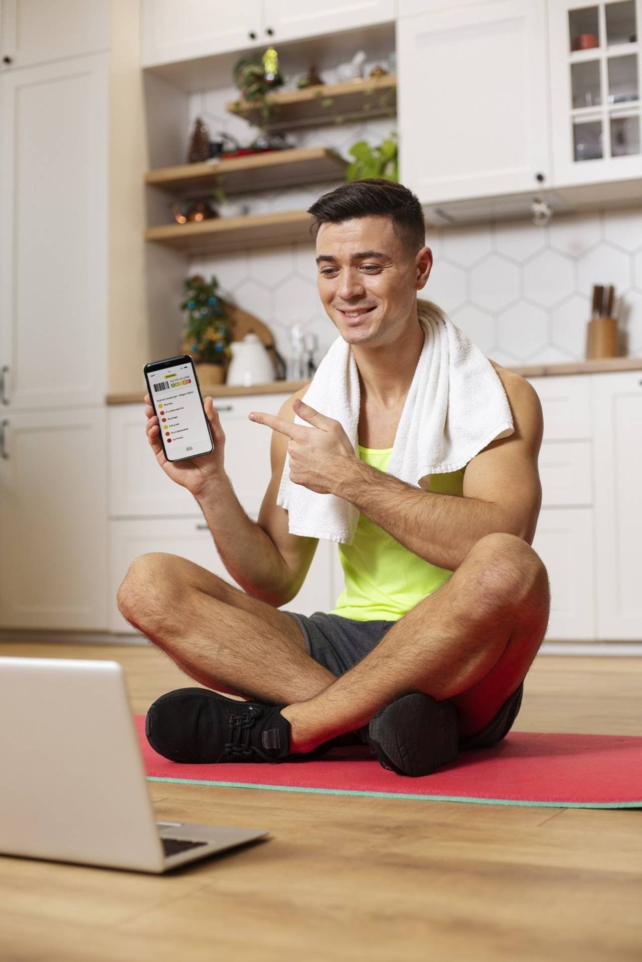 homem com roupa de academia sentado no chão mostrando a tela do celular