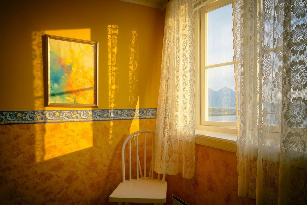 um ambiente com parede amarela e a cortina branca