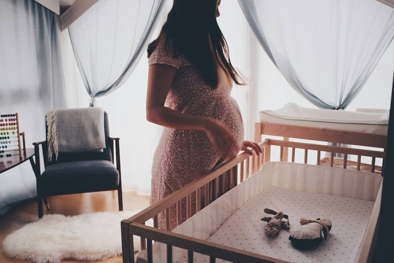 mulher gravida olhando para um berço