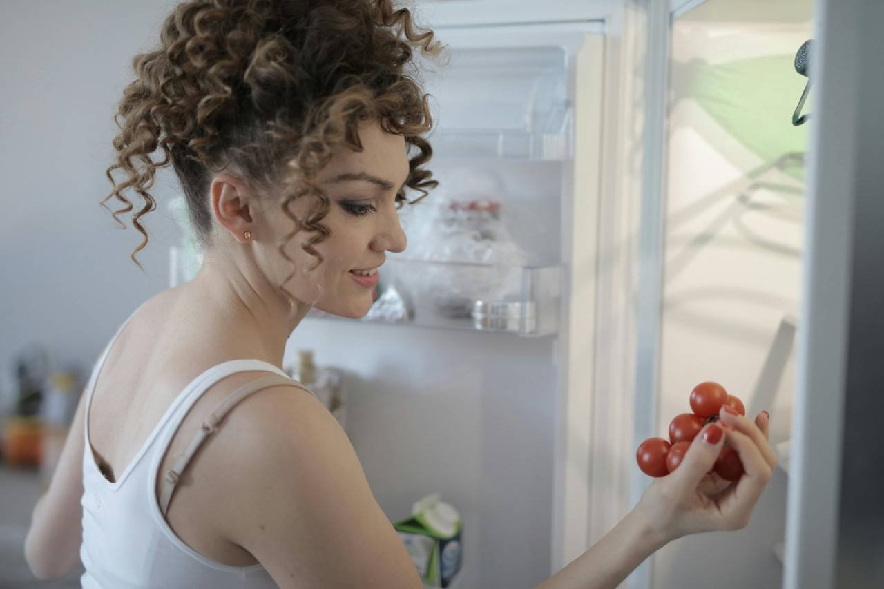 Mulher pegando produto dentro da geladeira