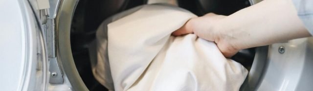 Pessoa colocando roupa branca na máquina de lavar