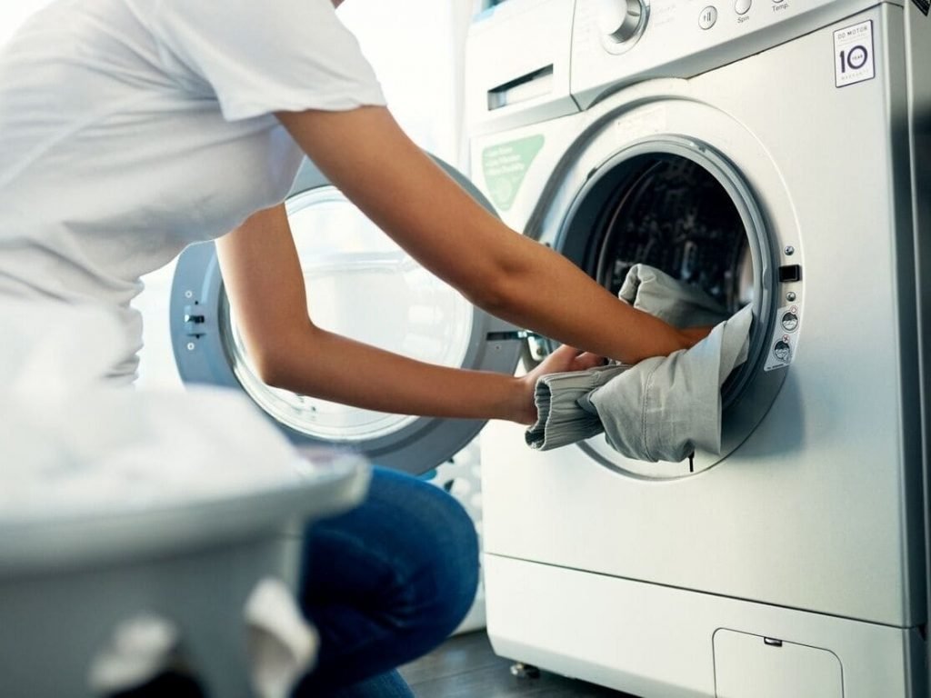 12 Pessoa colocando roupas na máquina de lavar