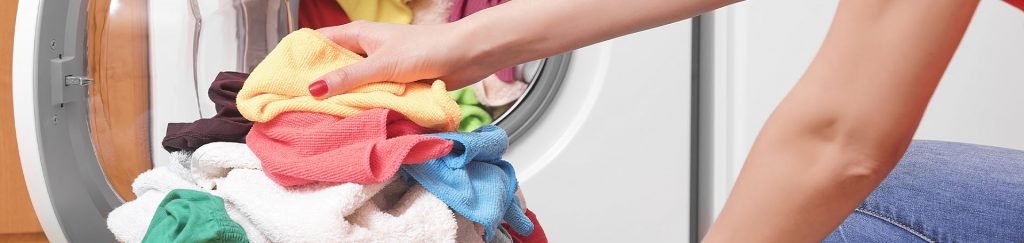 pessoa colocando roupas para lavar na máquina