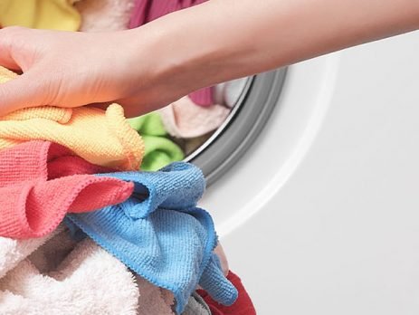 pessoa colocando roupas para lavar na máquina