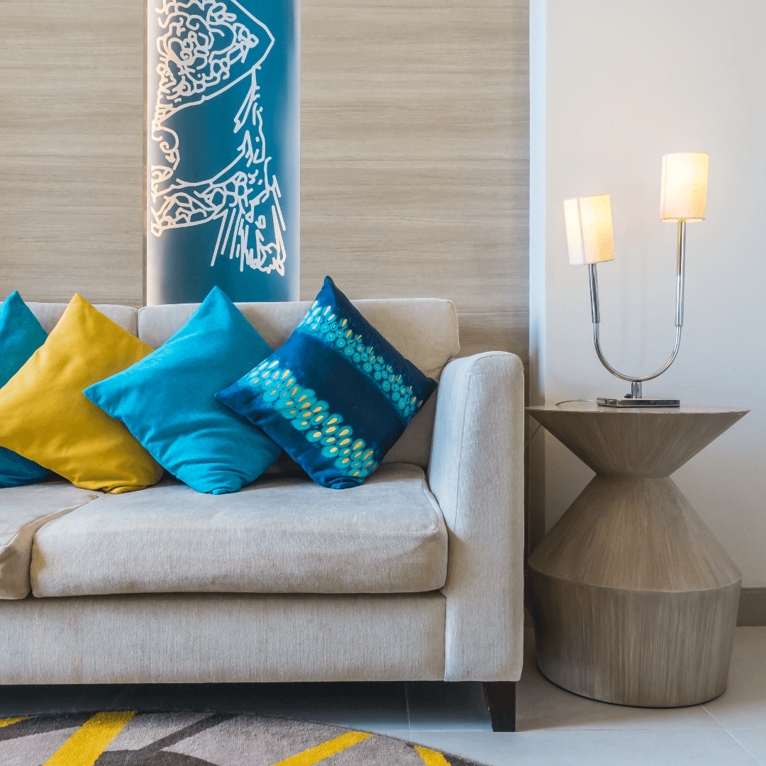 sofá neutro com almofadas coloridas, tapete geométrico e vaso 