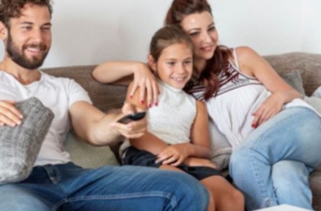 Familia assistindo TV em um sofá cinza