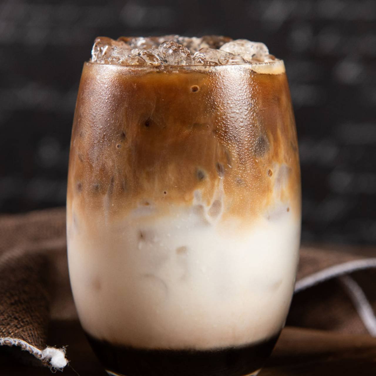 copo de vidro com café gelado cremoso com camada de leite 