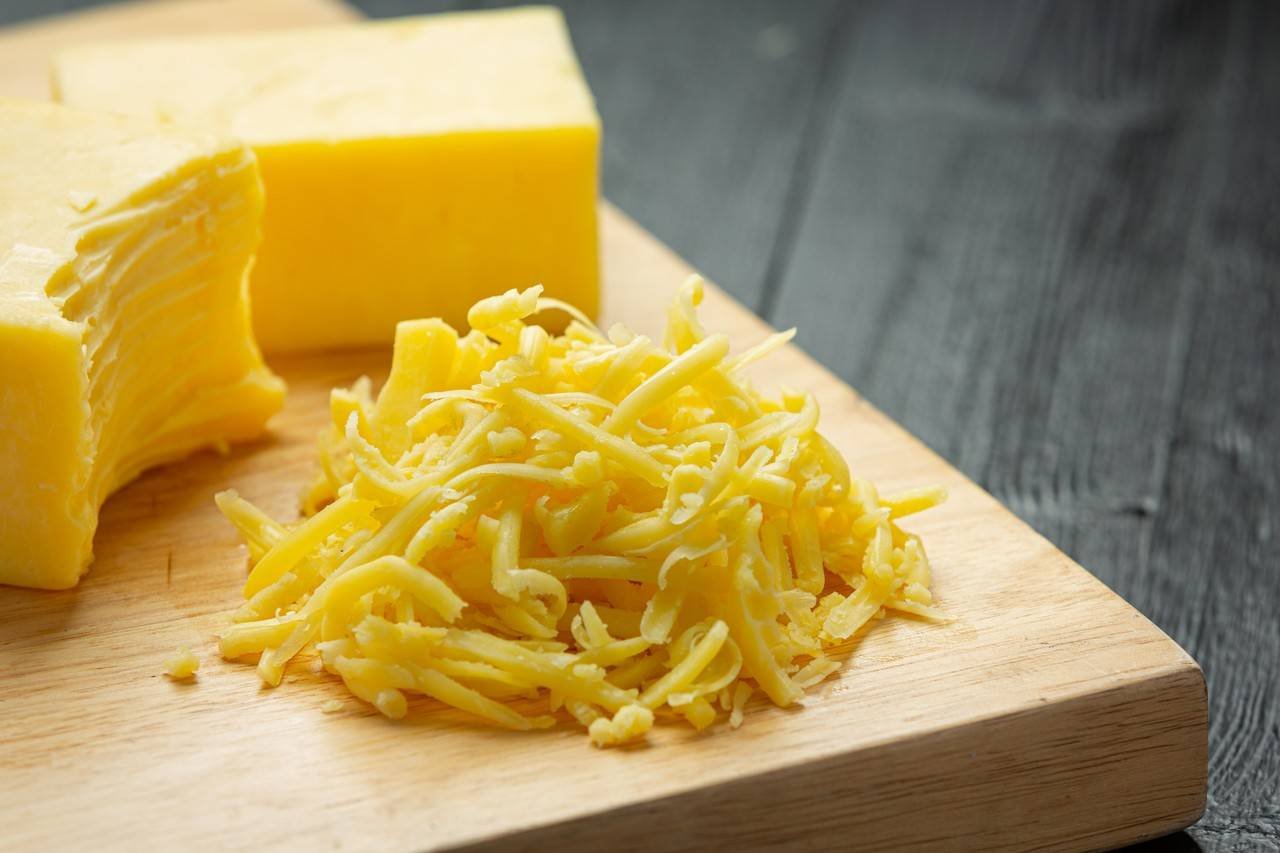 Tábua com queijo sendo fatiado 