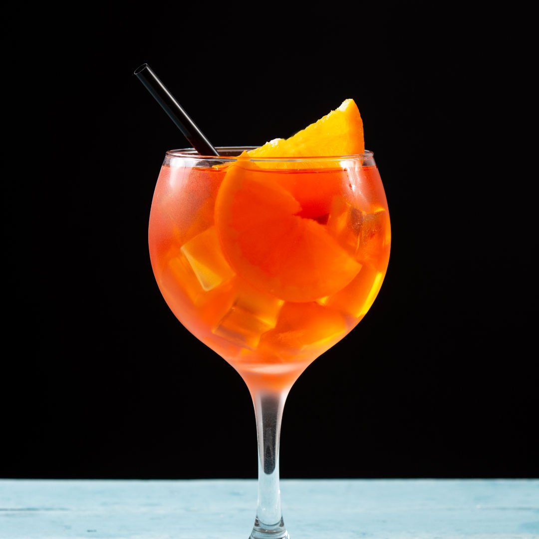 taça com drink de laranja e pedaços da fruta