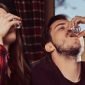 jovens amigos multirraciais bebem vodka descansando no pub