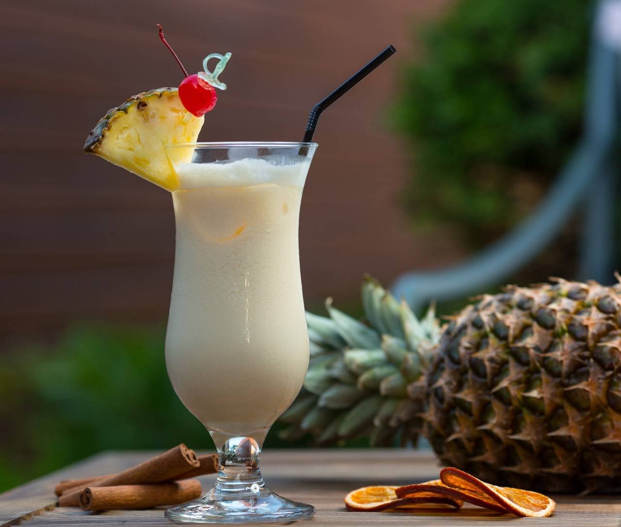 cocktail leitoso no copo com uma fatia de abacaxi e uma cereja