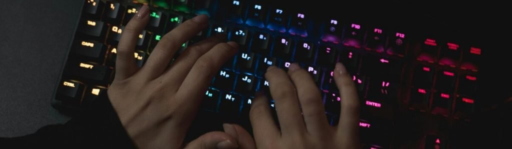 Pessoa digitando em um teclado RGB