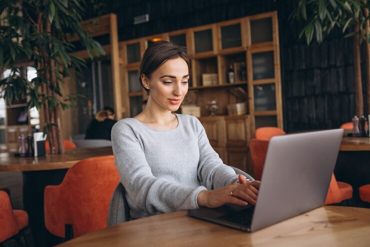 Mulher sentada em um café mexendo em um computador