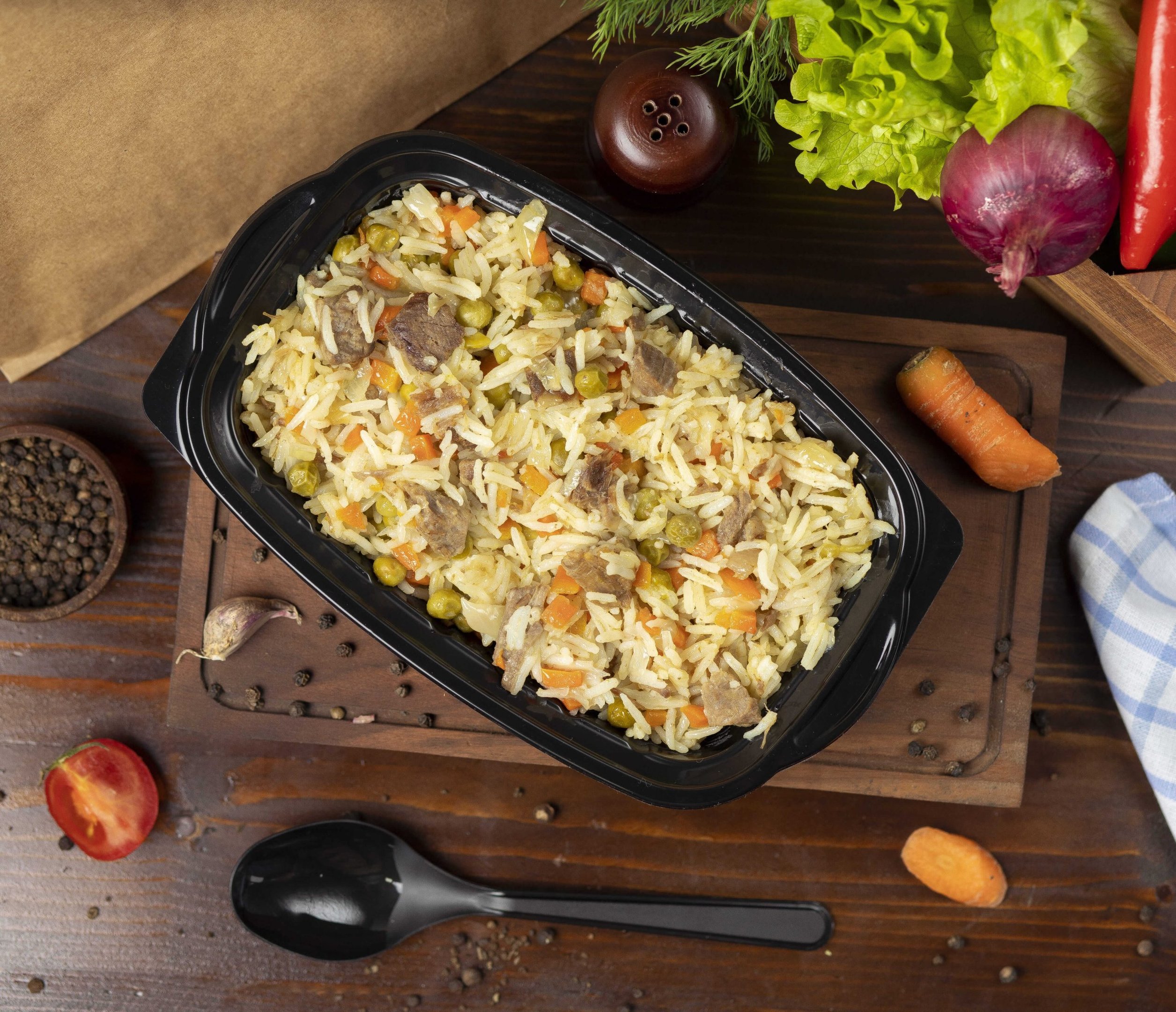recipiente preto com arroz carreteiro e outros alimentos em volta