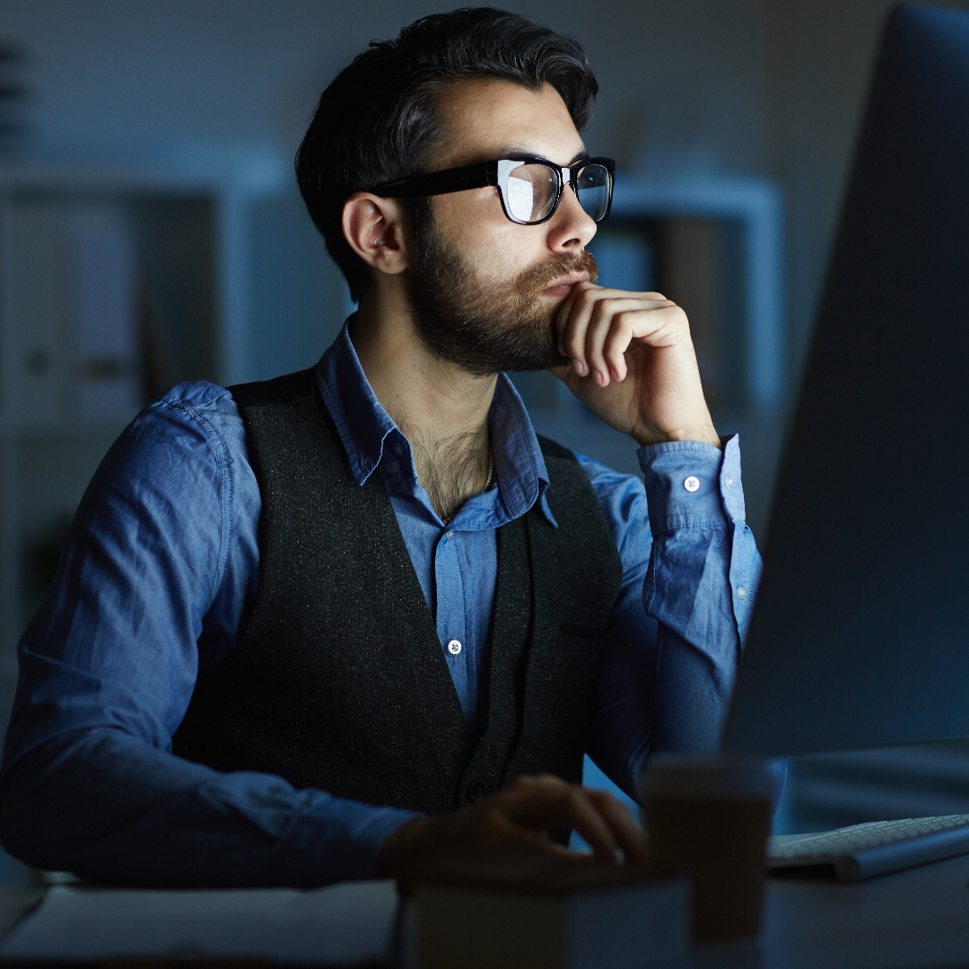homem com o cabelo escuro e óculos mexendo no computador 