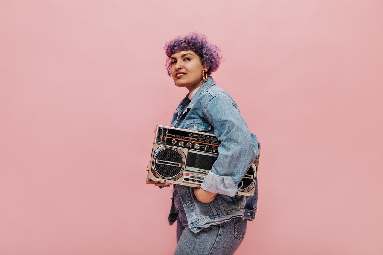 mulher com cabelo colorido segurando um rádio nos braços 
