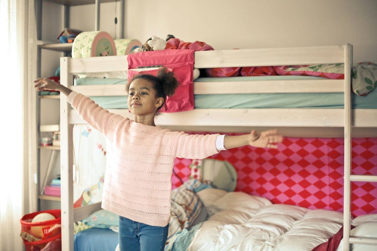 menina de braços abertos em seu quarto decorado