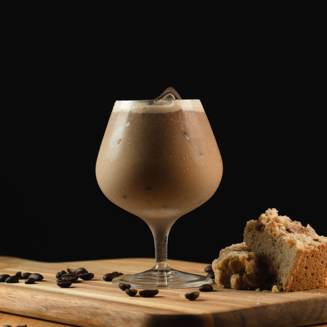 closeup tiro de um copo de cappuccino de gelo em uma placa de madeira com enfeites em preto 