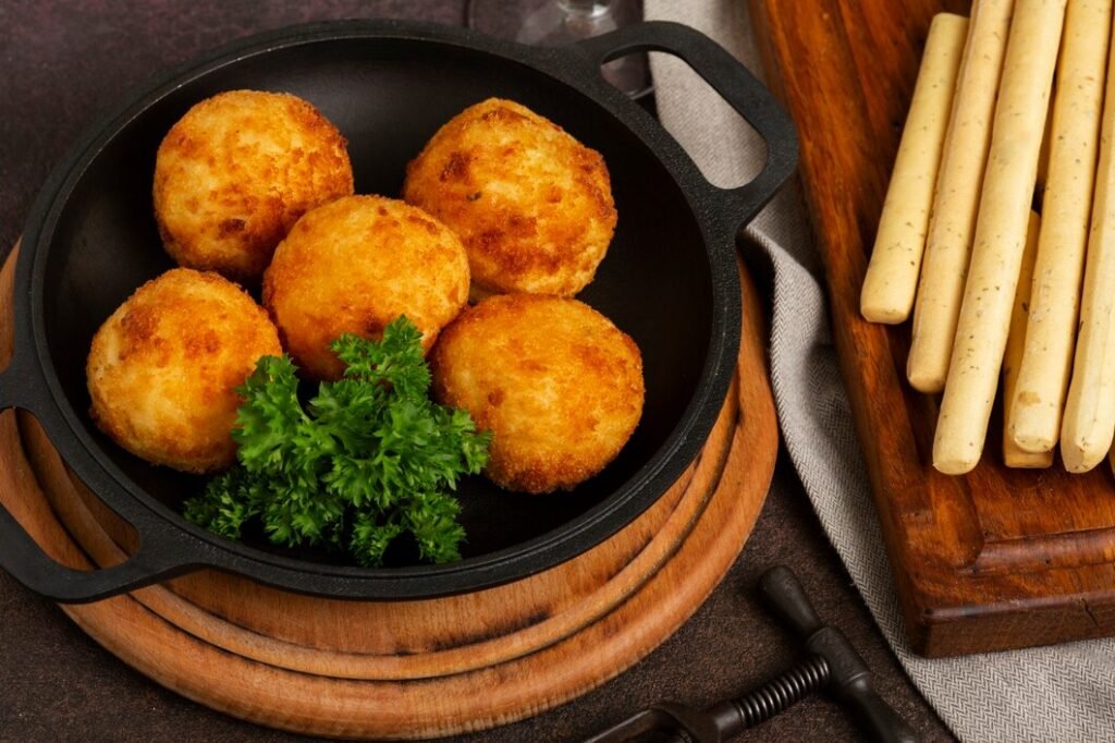 croquetes deliciosos de comida frita de angulo alto 23 2149202646 Bolinho frito crocante em uma panela de ferro