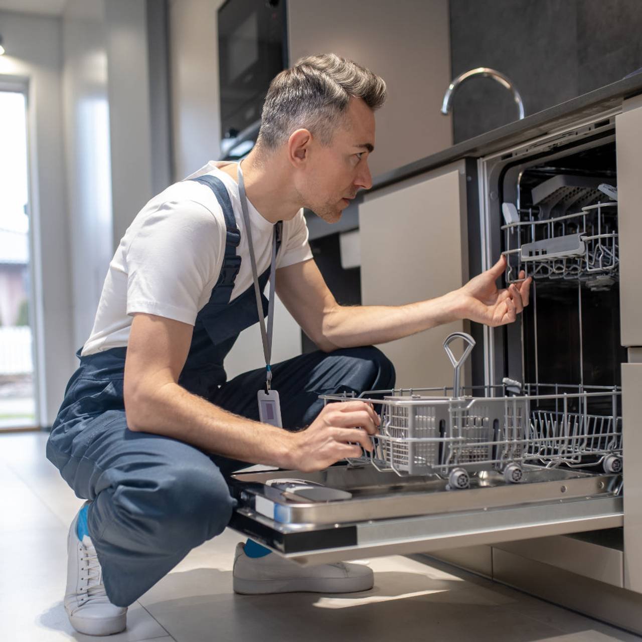 diagnostico de equipamento perfil de homem serio olhando para maquina de lavar louca aberta na cozinha (1)