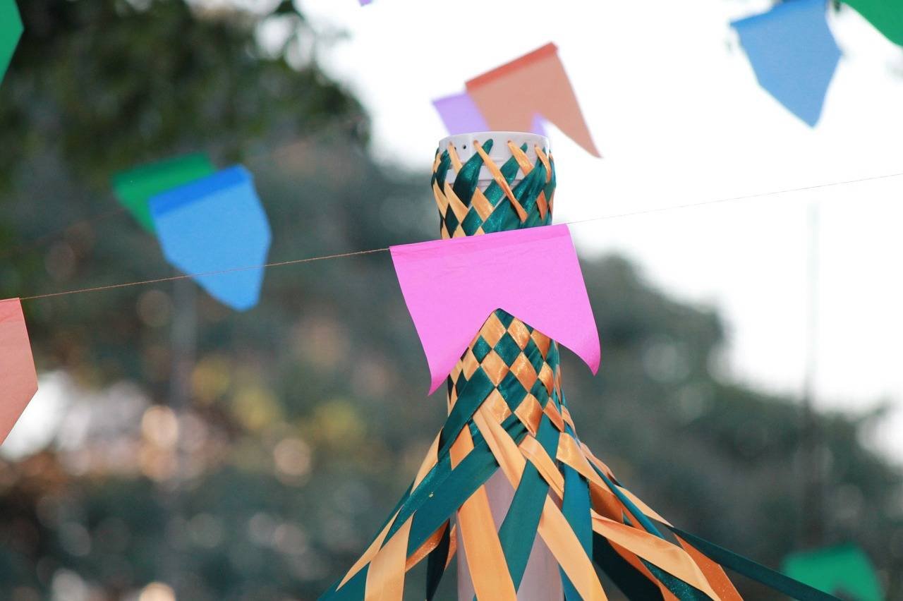 Bandeirinha rosa de Festa Junina pendurada próxima a outras decorações do evento
