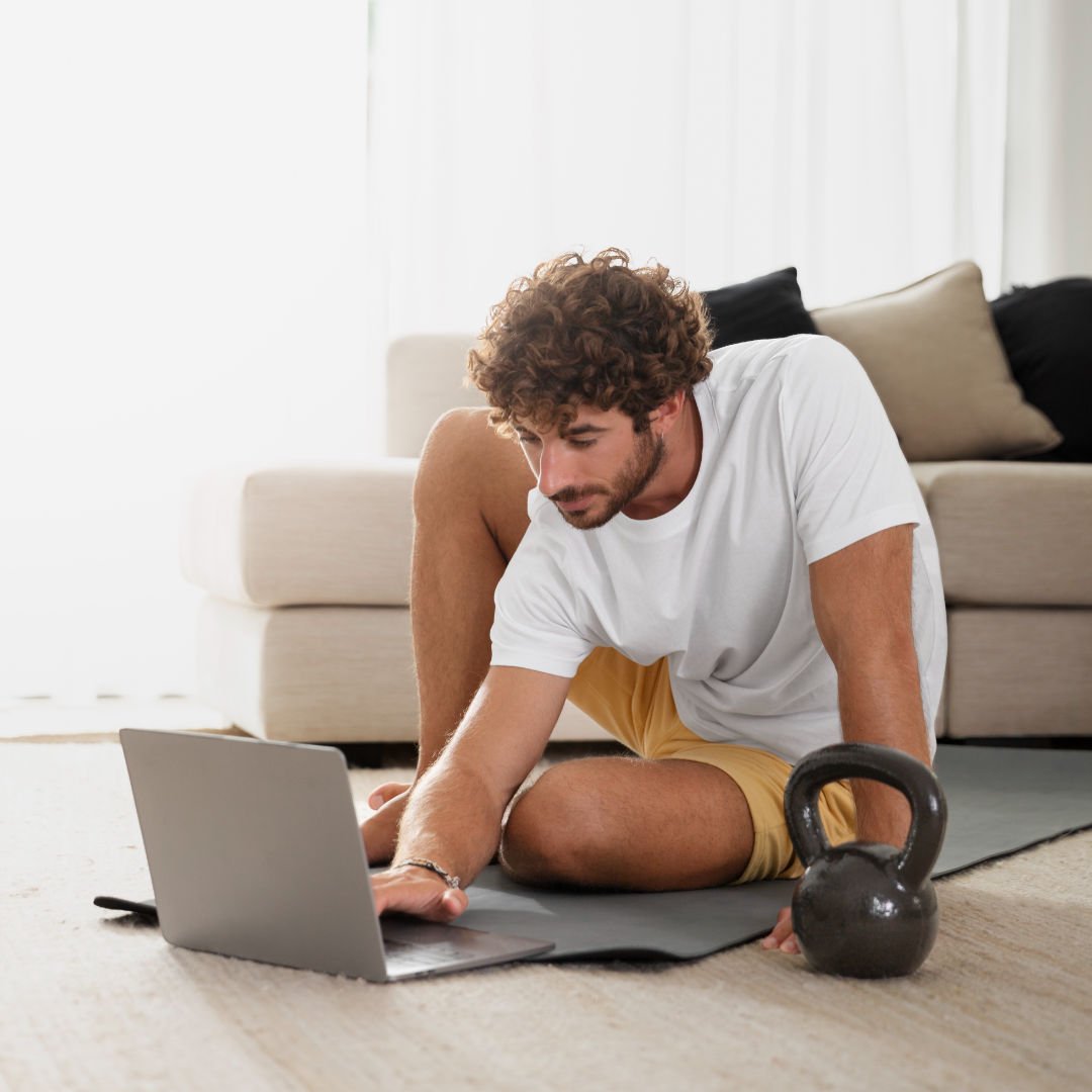 homem com roupa de academia mexendo no notebook no chão