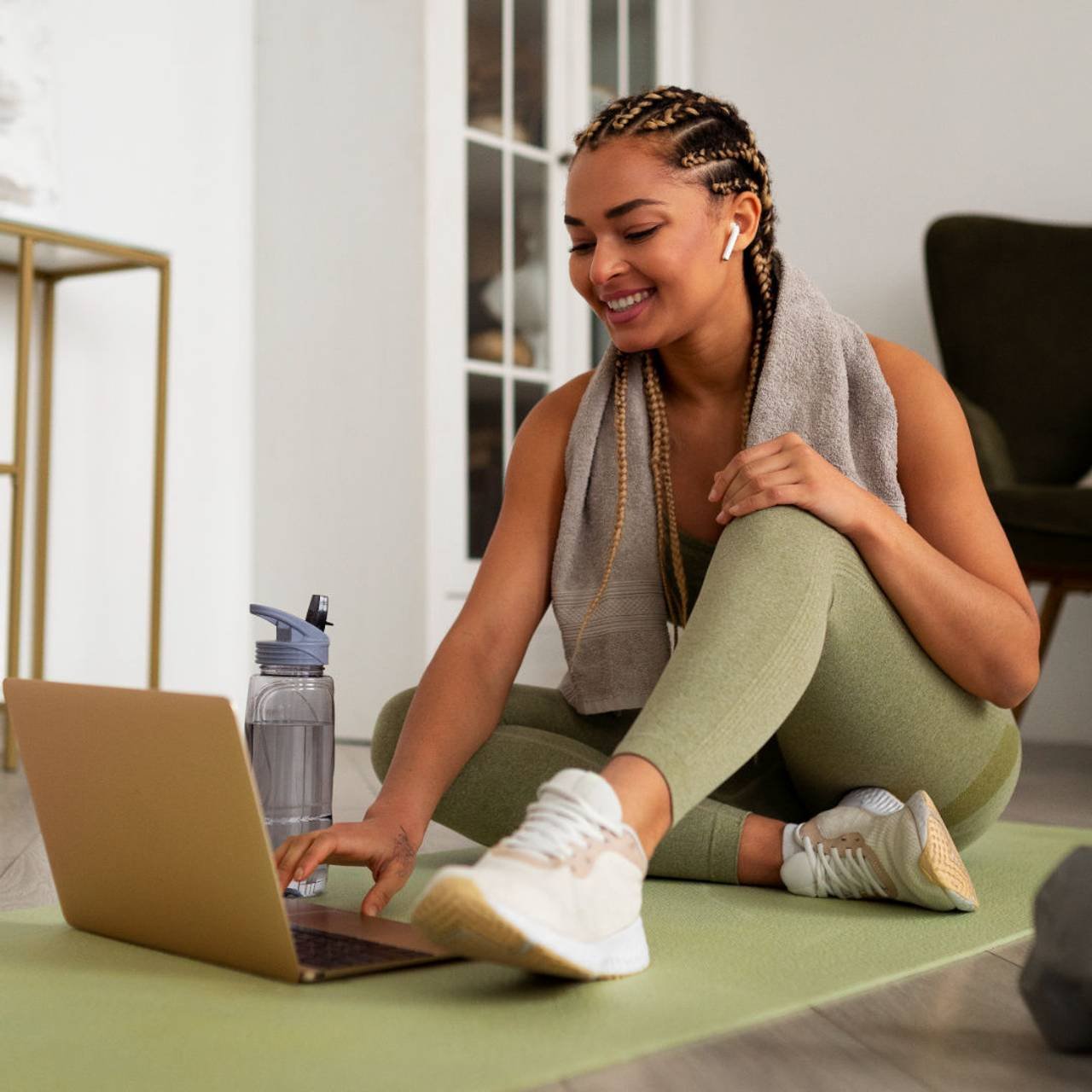 mulher com roupa de academia sentada no chão para mexer no notebook