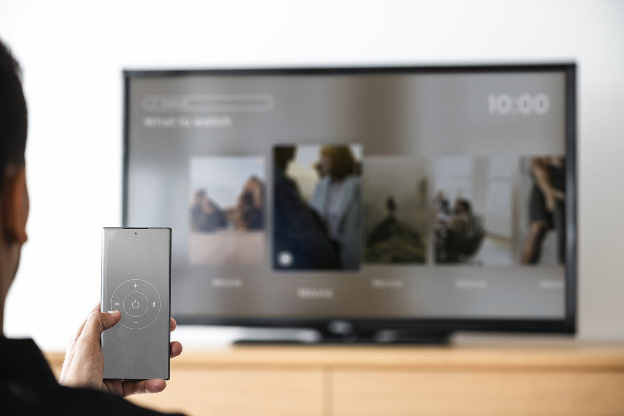 homem mudando de canal de tv pelo smartphone