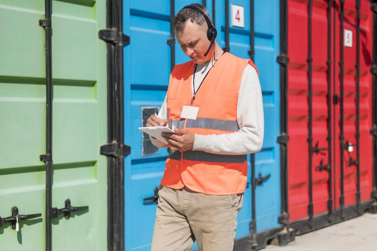 homem andando ao lado de containers