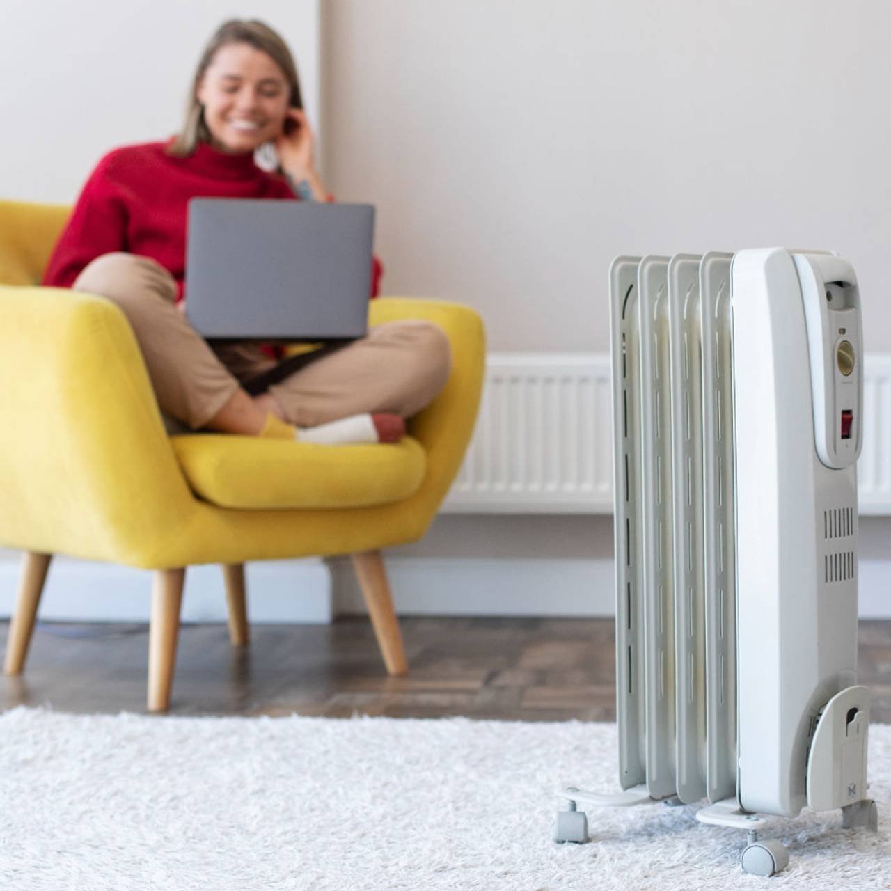 mulher mexendo em um notebook em uma poltrona amarela com climatizador na frente