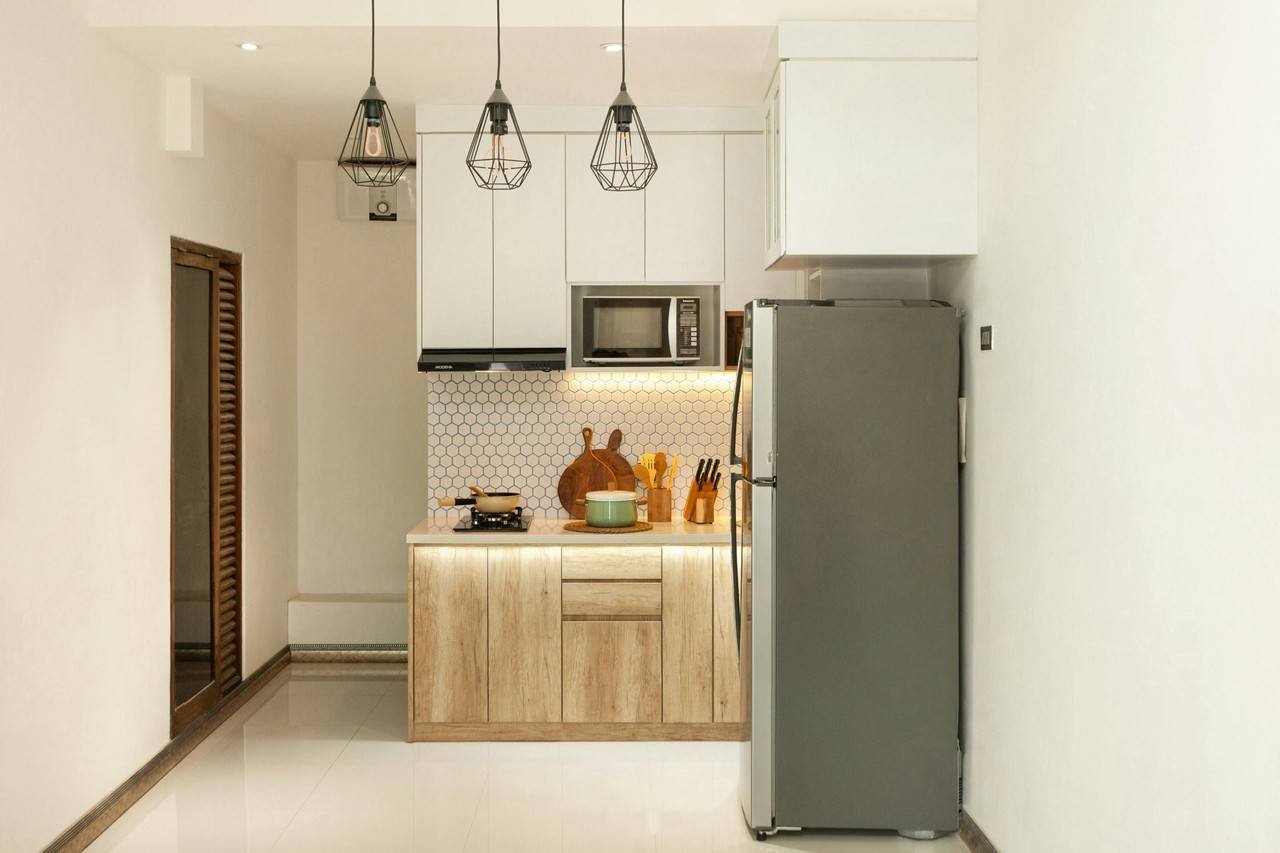 Cozinha pequena com decoração elegante, móveis de madeira, eletrodomésticos de inox e lustres pêndulos
