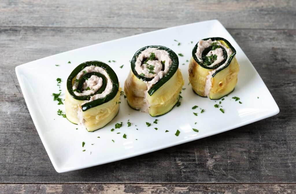 rolinhos de abobrinha grelhada recheados com cream cheese e atum na mesa de madeira 123827 22459 Rolinhos de abobrinha recheados com carne no prato