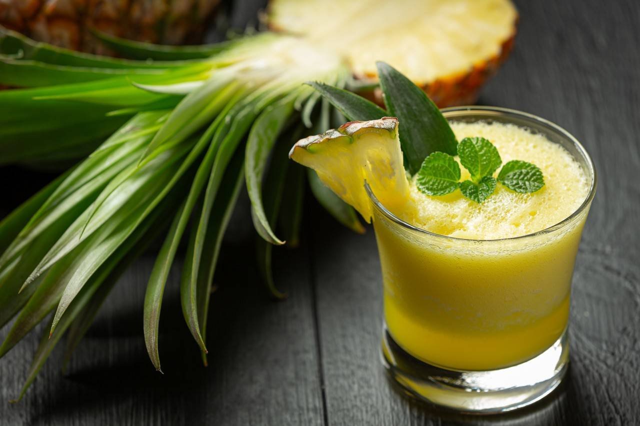 suco de abacaxi em superficie de madeira escura