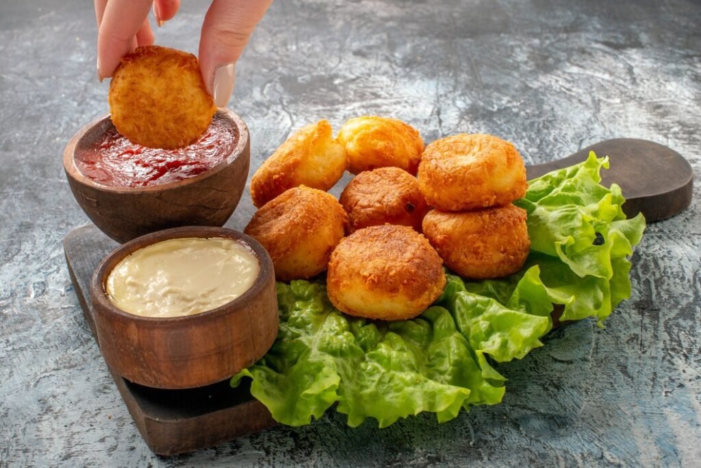 vista inferior bolinhas de queijo frito tigelas de molho de alface na tabua de cortar bolinho de queijo na mao feminina 140725 112106 Bolinho frito com molho e folhas de alface