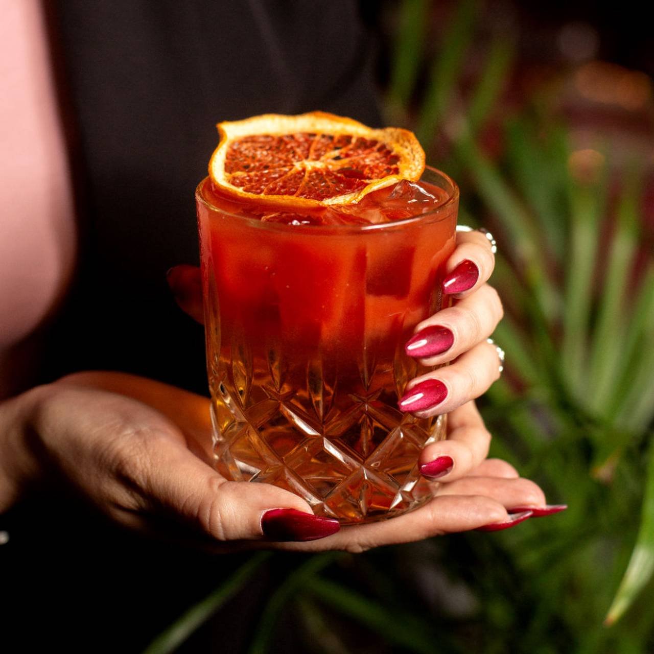 copo de vidro com drink negroni com laranja em cima