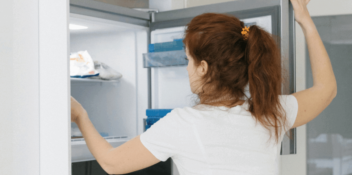 Mulher organizando alimentos em um refrigerador.