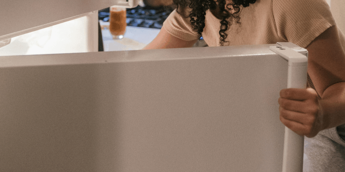 Pessoa abrindo a porta da geladeira na cozinha