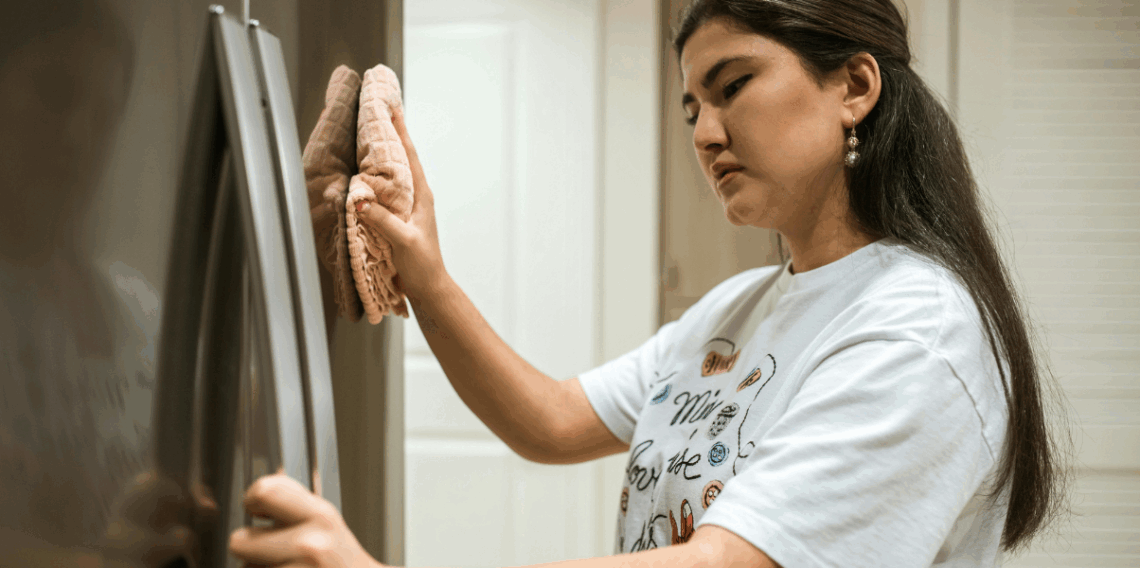 Mulher limpando refrigerador na cozinha