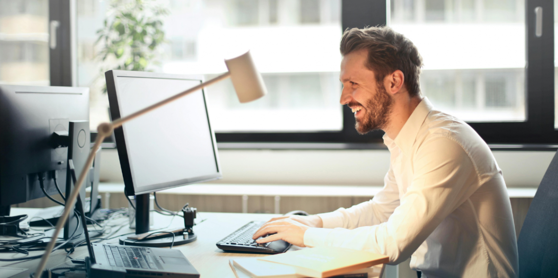 Homem sorrindo em escritório com computadores