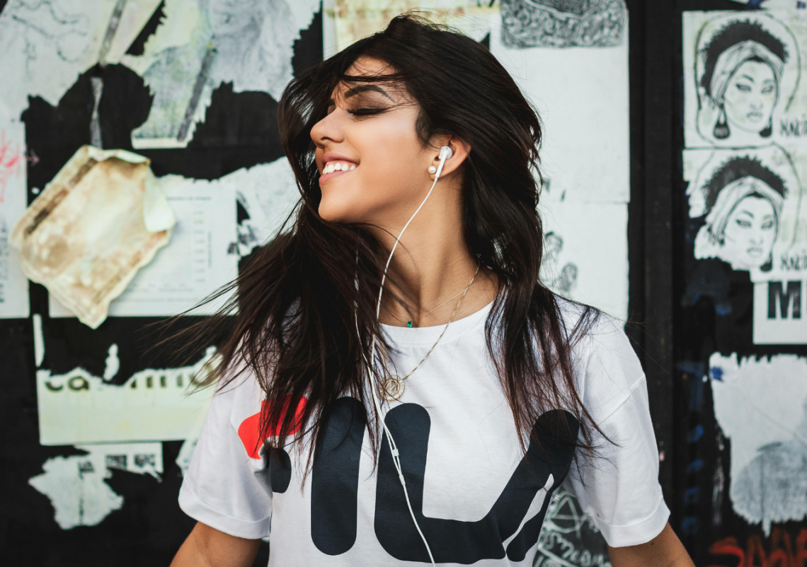 Modelodebullett.variadogrande13 Jovem sorrindo com fones de ouvido em ambiente urbano